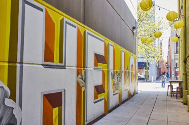 Sarı fenerler ve canlı şehir sanatı ile süslenmiş canlı bir Fort Wayne sokağındaki renkli Hello duvar resmi..
