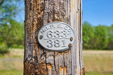 Rustic utility sign on a wooden pole in Warsaw, Indiana, symbolizing rural American life and land management. clipart