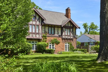 Güneşli bir gökyüzünün altında yemyeşil yemyeşil ile çevrili Güney Wayne Tarihi Bölgesi 'ndeki büyüleyici Tudor tarzı ev..