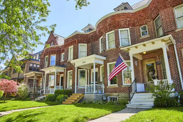 Fort Wayne 'deki güneşli banliyö caddesi geleneksel tuğla evler ve Amerikan bayrağıyla toplumu ve vatanseverliği simgeliyor..