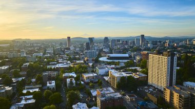 Gün doğumunda Portland, Oregon şehir merkezinin çarpıcı hava manzarası modern mimari, ağaçlarla kaplı sokaklar ve kayan tepelerin ve uzak dağların resimli arkaplanı. Şehir için mükemmel.