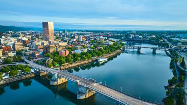 Portland, Oregon 'un çarpıcı hava manzarası, canlı şehir merkezi silueti, ikonik Morrison Köprüsü, ve sakin Willamette Nehri, şehir yaşamının ve doğal yaşamın karışımını yakalıyor.