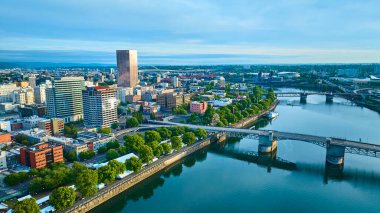 Portland, Oregon şehir merkezinin hava manzarası Willamette nehri kıvrılıyor. İkonik Morrison Köprüsü bu altın saatte yemyeşil ve somon renkli gökdelenlere karşı duruyor.