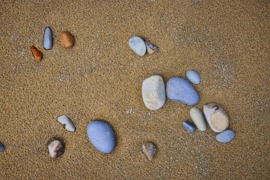Oregon 'daki Indian Beach' te altın kum üzerinde yumuşak çakıl taşlarının sakin yakın çekimi. Her taş eşsiz renk ve doku doğal bir mozaik oluşturuyor. Huzuru ve deniz kenarının güzelliğini taşımak için mükemmel.