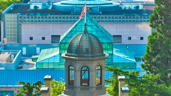 stock image Aerial view of downtown Portland Oregon showcasing the historic Pioneer Courthouse with its elegant dome juxtaposed against a modern glass building adorned with an American flag. Urban harmony of old