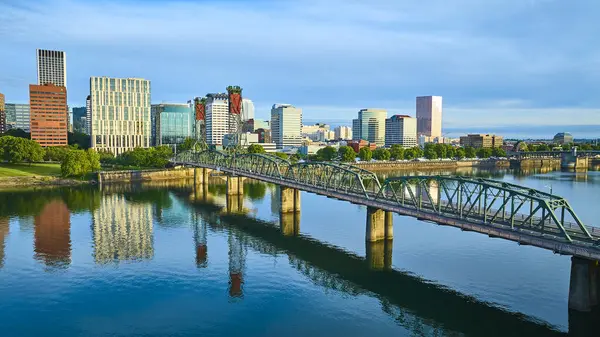 Portland, Oregon 'un havadan görünüşü Hawthorne Köprüsü' nü ve şehir merkezinin canlı ufuk çizgisini vurguluyor. Yumuşak ışıklandırma Willamette Nehri 'nin sakin yansımalarını güçlendiriyor, kentsel dinamizmi harmanlıyor.