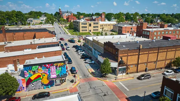 stock image Aerial view of Huntington Indianas downtown, featuring a vibrant mural with Yes You Can and a historic church amidst brick buildings and lush trees. Perfect for showcasing community charm and