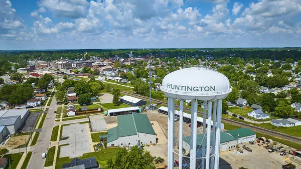 stock image Aerial view of Huntington, Indiana, featuring the iconic white water tower marked with HUNTINGTON in green, downtown buildings, and the serene river. A picturesque display of small-town American charm