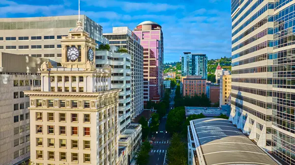 Tarihsel saat kulesi Portland, Oregon 'daki modern gökdelenlere karşı dimdik ayakta duruyor. Hava görüntüsü, parlak ve açık bir günde klasik mimari ve çağdaş ufuk çizgisinin karışımını yakalar..