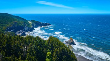 Samuel H. Boardman Eyalet Sahne Koridoru 'ndaki Thomas Creek Köprüsü' nün engebeli kıyı şeridini gösteren hava manzarası. Yeşil kayalıklar Pasifik 'le buluşuyor, aşağıdaki dalgalar çarpıcı bir doğal afet yaratıyor.
