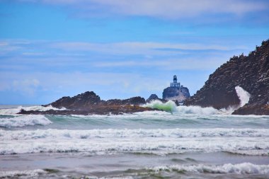 Oregon, Indian Beach 'teki Majestic deniz feneri çarpan dalgalara ve engebeli kıyı şeridine karşı dirençli. Kılavuz, güvenlik ve keşif temalarını sergilemek için mükemmel sakin bir sahil sahnesi..
