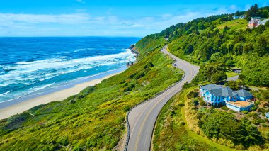 Oregonlar 'ın havadan görünüşü dolambaçlı bir yol, dingin bir plaj ve kayalıklardaki çarpıcı mavi bir ev ile bereketli kıyı manzarası ve nefes kesici doğal güzellikler sunuyor. Yolculuk için mükemmel.
