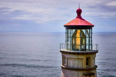 Floransa, Oregon 'daki Heceta Baş Feneri' ne yakın çekim. Kırmızı kubbeli ve ışıl ışıl fener odalı klasik mimari sakin bir okyanus zeminine karşı duruyor.