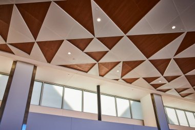 Minneapolis havaalanında, geometrik ahşap ve beyaz paneller, durgun ışıklandırma ve büyük pencerelerden gelen doğal ışık içeren modern tavan tasarımı. Bu sofistike iç mekan mimariyi ön plana çıkarıyor