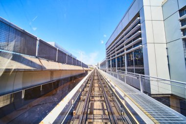 Ufuk çizgisine doğru uzanan Minneapolis kentsel tren yolunun dinamik manzarası. Modern binalar, berrak mavi gökyüzü ve hareket hissi verimli ve sürdürülebilir şehrin özünü yakalıyor.