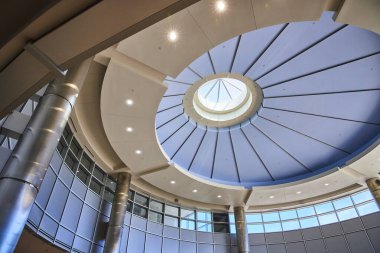 Çarpıcı dairesel çatı penceresi, sağlam metalik sütunları ve yansıtıcı cam panelleri bulunan Minneapolis havaalanındaki şık modern mimari. Tasarım yenilik, açıklık ve gelişmiş