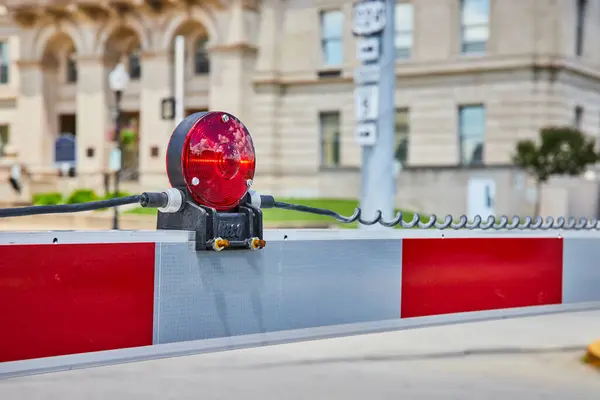 stock image Vivid red warning light on a metallic barrier with reflective stripes in front of the historic Huntington County Superior Court in Indiana. The image emphasizes security and restricted access in an