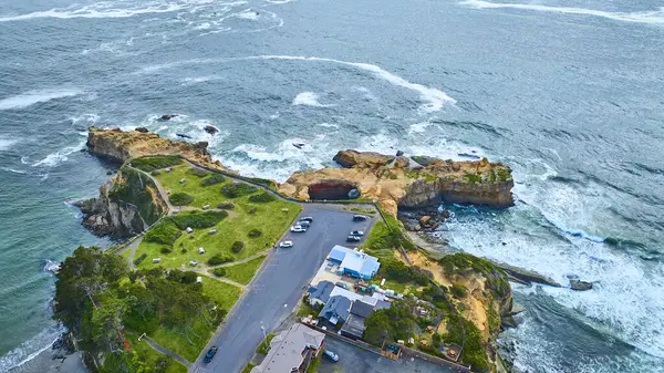 Oregon, Otter Rock 'taki Devils Punchbowl' un hava görüntüsü. Engebeli kıyı şeridini, kayalıklarla buluşan dramatik okyanus dalgalarını ve küçük bir sahil topluluğunu yakalıyor. Seyahat, emlak ve doğa için mükemmel.