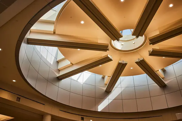 stock image Modern architecture at Minneapolis airport showcases an intricate ceiling design with a central circular opening, natural light, and warm beige-brown tones, creating a spacious and tranquil atmosphere