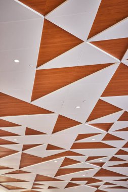 Minneapolis havaalanında geometrik desenli ve sıcak ahşap tonlu modern tavan tasarımı. Gömülü aydınlatma ile çağdaş mimari hem estetik hem de fonksiyonu geliştirir, bir davet yaratır