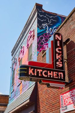 Huntington, Indiana şehir merkezindeki canlı şehir manzarasında Nicks Kitchen 'ın ikonik kırmızı neon işareti ve renkli bir duvar resmi var. Klasik Americana ve modern sokak sanatının mükemmel bir karışımı..