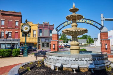 Huntington şehir merkezindeki Rotary Centennial Park 'ta büyüleyici bir manzara, tarihi bir saat, canlı bir su çeşmesi, ve açık mavi gökyüzü altında renkli binalar, küçük kasaba cazibesini ve