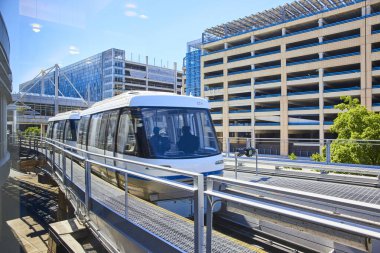 Gösterişli otomatik insanlar Minneapolis havaalanındaki hareketli bir şehir taşıma sahnesinde süzülüyor. Modern tasarım, yansıtıcı cam cepheleri ve parlak güneşli gökyüzü yenilik temaları vurguluyor ve