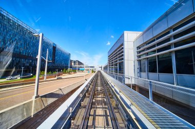 Minneapolis kentsel iş bölgesindeki bir tren yolunun dinamik manzarası, berrak mavi gökyüzü altında eşsiz mimarisi olan modern binalarla çevrili. Kentsel gelişim temaları için mükemmel.