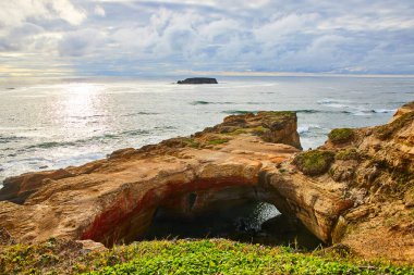 A breathtaking view of Devils Punchbowl at Otter Rock, Oregon. The striking rock archway, vibrant coastal hues, and serene ocean waves reflect the tranquil power of the West Coast seascape. clipart