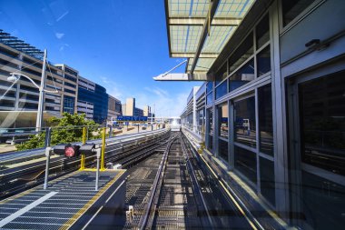 Minneapolis, Minnesota 'daki modern şehir tren istasyonu, parlak cam paneller sergileniyor, raylar kesişiyor ve parlak bir gökyüzünün altında yaklaşan bir tramvay. Bağlantı ve hareketlilik temaları için mükemmel