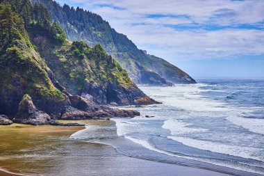Oregon sahilindeki Heceta Head Deniz Feneri 'nin nefes kesici manzarası. Bereketli yeşilliği olan dramatik uçurumlar çalkantılı okyanus dalgalarıyla karşılaşıp doğaları evcilleştirilmemiş güzellik ve sükuneti yakalıyor. Seyahat için ideal