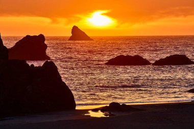 Oregon 'daki Harris Beach State Park' ta gün batımı dramatik kaya oluşumlarıyla nefes kesici deniz manzaraları yakalıyor. Canlı turuncu gökyüzü ve sudaki altın yansımalar huzuru ve korkuyu anımsatıyor, mükemmel.