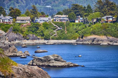 Berrak mavi suları ve varlıklı evlerin altına dağılmış kayalıkları olan sakin sahil koyunda kayalıklar. Yeşillik ve dolambaçlı merdiven Brookings, Chetco Point Park 'taki bu sakin sahneye cazibe katar.