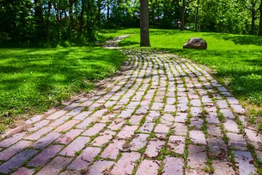 Serene kaldırım taşı yolu Huntingtons Memorial Park, Indiana 'daki yemyeşil alandan geçiyor. Güneşli ağaçlar ve ıssız bir kaya, sakin bir ortam yaratır, sakin yürüyüşler ve huzur verici yürüyüşler için mükemmeldir.