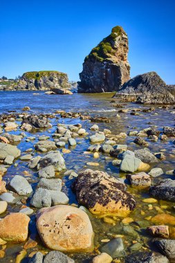 Brookings, Oregon 'daki Harris Beach State Park' taki kıyı kaya oluşumlarının nefes kesici görüntüsü. Yükselen yekpare ve dingin sular, doğa, seyahat ve macera için mükemmel bir zıtlık yaratır.