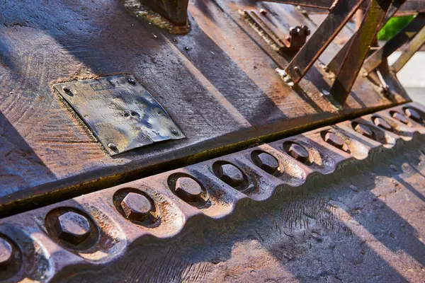 Stock image Close-up of a weathered metal structure with a brass plaque, showcasing industrial texture against a rusted backdrop. Features circular cut-outs and evokes themes of history, decay, and industrial