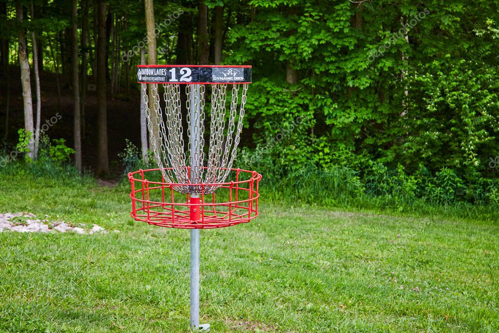 Disc golf basket number 12 in vibrant Memorial Park, Huntington, Indiana. Surrounded by lush greenery, this serene setting is perfect for outdoor sports and community leisure activities.