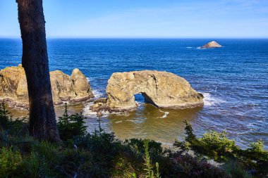Oregon 'daki Samuel H Boardman Eyalet Sahne Koridoru' nda Arch Rock 'ın sakin sahnesi. Güneşli kaya oluşumları ve derin mavi okyanusa karşı doğal bir kemer huzuru ve doğal güzelliği çağrıştırıyor..