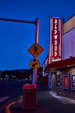 Redwood Tiyatrosu 'nun tabelası sessiz caddeyi aydınlatırken, alacakaranlık Oregon şehir merkezine iniyor. Yaya geçidi tabelası bu nostaljik akşam sahnesine küçük kasaba cazibesini katıyor..