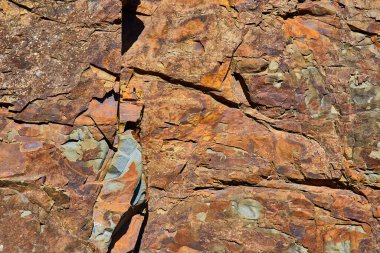 Oregon 'daki Chetco Point Parkı' nda engebeli çok renkli kaya oluşumlarının yakın çekimi. Gri ve mavimsi tonlara sahip zengin kahverengi ve turuncu renkler dinamik bir jeolojik tarihi ortaya koymaktadır. Doğal projeler için mükemmel.