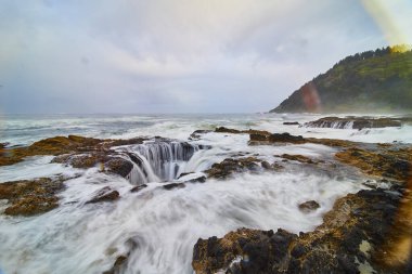 Thors 'un saf gücüne ve güzelliğine tanık olun. Oregon, Yachat' ta dalgalar yumuşak bir gökkuşağı altında engebeli kayaların üzerine çökerken doğanın özünü yakalıyor. Acımasız enerji ve huzurlu sahil cazibesi.