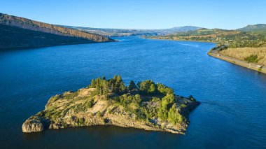 Merkezinde bereketli tepeler ve engebeli uçurumlarla çevrili pitoresk bir adanın bulunduğu sakin Columbia Boğazı 'nın havadan görünüşü. Oregon 'daki sakin nehir ve manzara mükemmel bir karışım sunuyor.