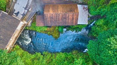 Washington 'daki Cedar Creek Grist Mill' in hava manzarası yemyeşil bir nehrin ortasındaki tarihi bir değirmeni gösteriyor. Sakin ve kırsal ortam, doğanın güzelliğini ve sanayi mirasını ön plana çıkarıyor.
