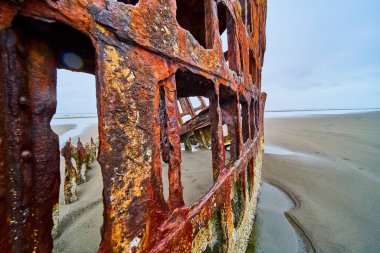 Hammond, Oregon 'da sakin bir sahilde, Peter Iredale' in enkazından geriye kalan paslı kalıntılar. Çürümenin güzelliğini yakalamak ve zamanın geçişini sonsuz kum ve bulutlu gökyüzünün arka planına karşı..