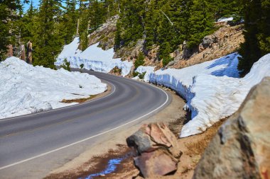 Oregon 'daki, kar kaplı Krater Gölü Ulusal Parkı' nda dolambaçlı bir dağ yolunun dingin güzelliğini tecrübe edin. Bitmeyen yeşil orman ve açık mavi gökyüzü unutulmaz bir kış macerası vaat ediyor..