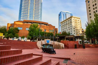 Pioneer Adliyesi Meydanı, Portland 'da sabah sakinliği: kırmızı tuğla amfi tiyatro, heykeller, bayraklar ve Starbucks' ın yer aldığı modern ve geleneksel mimarinin bir karışımını sergileyen sakin bir şehir meydanı.