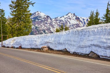 Oregon 'daki Krater Gölü Ulusal Parkı' nda yüksek kar yığınları ve görkemli kar tepeleriyle çevrili dolambaçlı bir dağ yolu var. Seyahat ve macera meraklıları için mükemmel.