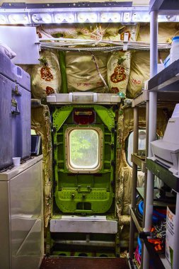 Portland, Oregon 'daki Airplane House' da bir uçak bakım alanında aletler, ekipmanlar ve canlı yeşil bir kapı. Aydınlatılmış, dağınık alan sahne arkasındaki karmaşıklığı ortaya çıkarıyor.