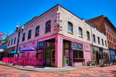 Portland, Oregon 'da canlı bir sokak sahnesi, ikonik Voodoo Donutu' nun çarpıcı pembe cephesi ve renkli açık hava oturma alanı. Kentsel yaşam tarzı ve kültürel yaşam için mükemmel