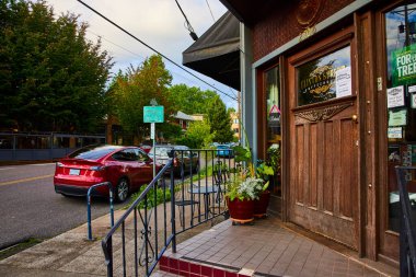 Süslü ahşap kapısı ve kapalı tabelası ile Charming Clinton Street Kafe, Portland, Oregon şehir merkezinde, canlı kırmızı Tesla ve bereketli ağaçlar ile yan yana.